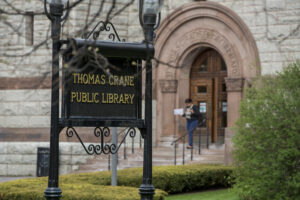 outdoor photo of library name sign on the Olmsted Lawn with the Coletti entrance of the library in the background