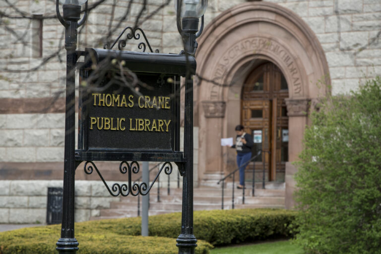 outdoor photo of library name sign on the Olmsted Lawn with the Coletti entrance of the library in the background